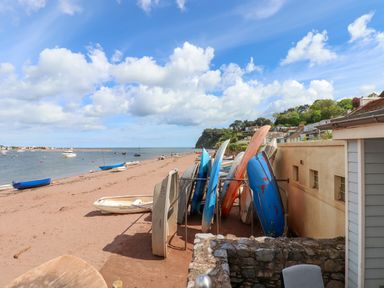 A beach with boats on the sand and in the water alongside a row of houses at Beach Hut 5 in Shaldon