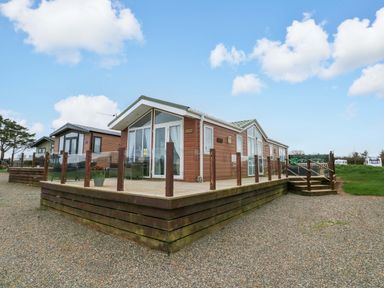 A wooden lodge with decking and steps at Gentle Tide in Hasguard Cross near Little Haven
