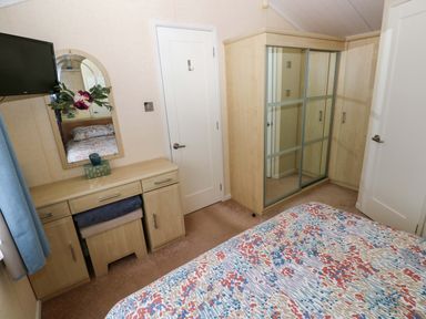 A bedroom with a dresser and mirror at Gentle Tide Hasguard Cross near Little Haven