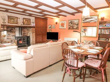 A living room with a dining table set with plates and glasses a fireplace and a television at Loanview in Cornhill-On-Tweed