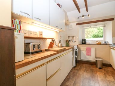 A kitchen with wooden countertops a toaster electric kettle knives and a window with kitchen utensils at Loanview in Cornhill-On-Tweed