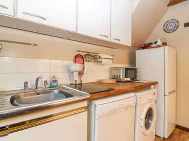 A small kitchen area with a sink, washing machine, dishwasher, microwave, and refrigerator at Loanview in Cornhill-On-Tweed