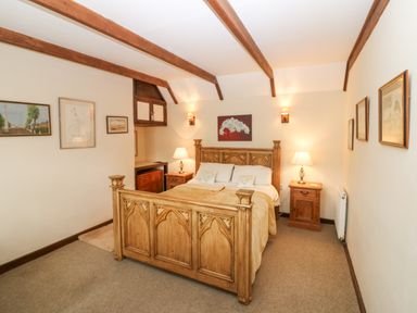 A bedroom with a wooden bed and bedside tables with lamps at Loanview in Cornhill-On-Tweed