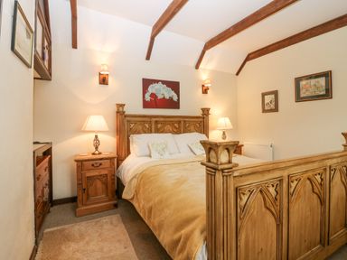 A bedroom with a wooden bed frame bedside tables lamps and wall art at Loanview in Cornhill-On-Tweed