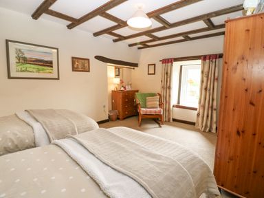 A bedroom with two single beds a wooden chair a chest of drawers and a wardrobe at Loanview in Cornhill-On-Tweed