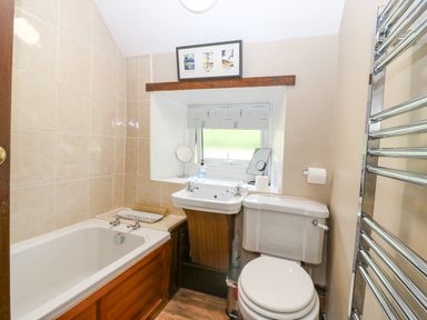 A bathroom with a bathtub a sink a toilet a window with a blind and a heated towel rail at Loanview in Cornhill-On-Tweed