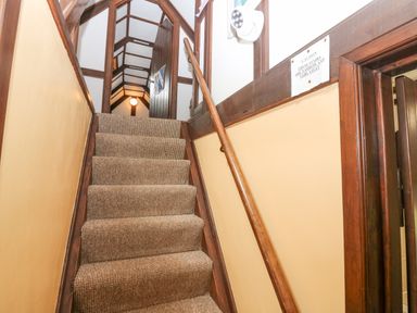 A narrow carpeted staircase with wooden handrail and walls at Loanview in Cornhill-On-Tweed