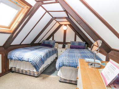 A bedroom with two single beds with plaid bedding and a wooden dresser at Loanview in Cornhill-On-Tweed
