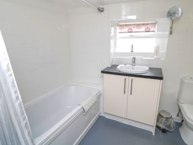 A bathroom with a bathtub sink cabinet and toilet at White Swan Cottage in Alnwick