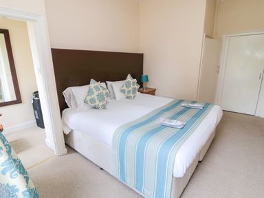 A bedroom with a double bed with blue and white pillows and a blue striped runner at White Swan Cottage in Alnwick