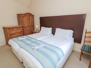 A bedroom with two single beds pushed together next to wooden furniture at White Swan Cottage in Alnwick
