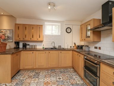 A kitchen with wooden cabinets a double oven a sink under a window patterned floor tiles and kitchen appliances at The Fullerton in Belsay