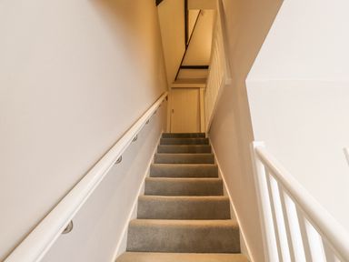 A carpeted staircase with white handrails leading to a closed door at The Fullerton in Belsay