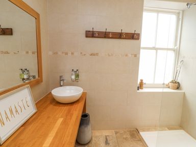 A bathroom with a round sink on a wooden countertop and a framed namaste sign at The Fullerton in Belsay