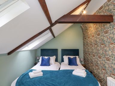 A bedroom with two single beds under a sloped ceiling with exposed wooden beams at The Fullerton in Belsay