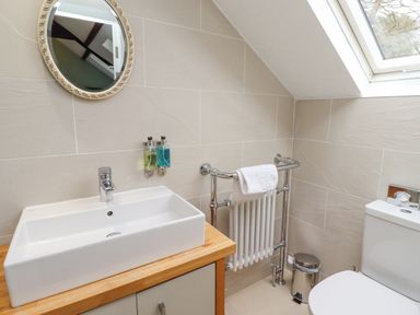 A bathroom with a sink a mirror a towel rack a toilet and a skylight window at The Fullerton in Belsay
