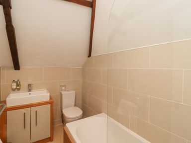 A bathroom with a sink cabinet toilet and bathtub with glass partition at The Fullerton in Belsay