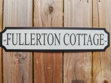 A wooden fence with a sign reading Fullerton Cottage