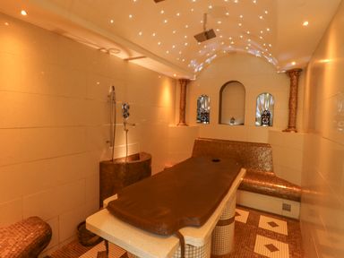 A spa room with a massage table shower and mosaic tiled seats at The Fullerton in Belsay