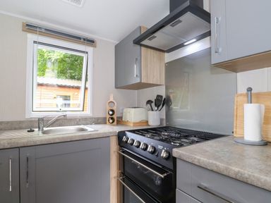 A kitchen with a gas stove oven sink window and kitchen utensils at Eltons Escape Pony Meadow 3 White Cross Bay near Windermere
