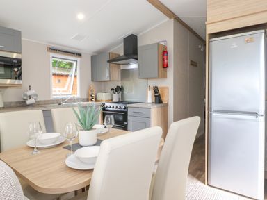 A kitchen and dining area with a table set for four and appliances at Eltons Escape in Pony Meadow 3 White Cross Bay near Windermere