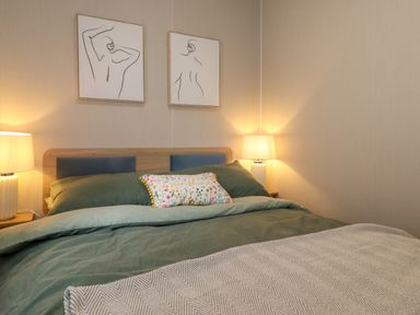 A bedroom with a bed with green bedding and two lamps on bedside tables at Elton's Escape in Pony Meadow 3 White Cross Bay near Windermere