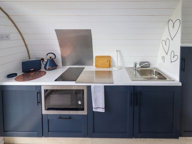 A kitchen counter with a microwave oven toaster kettle stovetop sink and cutting boards at Moel Famau in Bryniau Clwyd near Denbigh