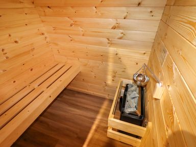 A wooden sauna room with a bench and a heater with stones at Moel Famau in Bryniau Clwyd near Denbigh
