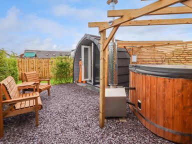 An outdoor space with wooden chairs a wooden hot tub a curved cabin and a wooden fence at Moel Famau in Bryniau Clwyd near Denbigh
