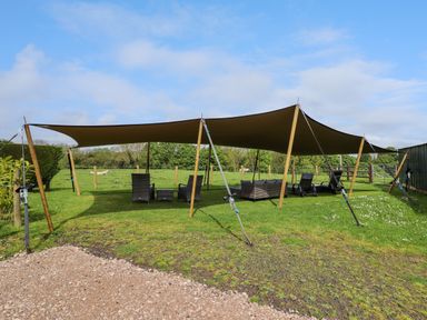 An outdoor seating area with canopy, chairs, and tables on grass at Moel Famau in Bryniau Clwyd near Denbigh