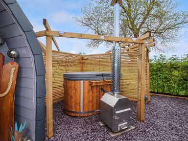An outdoor wooden hot tub with a metal heater and wooden privacy screen at Moel Arthur in Bryniau Clwyd near Denbigh
