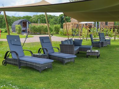 Outdoor seating area with lounge chairs sofas and tables on grass under a canopy at Moel Arthur Bryniau Clwyd near Denbigh