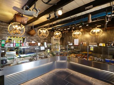 An interior of a small shop with seafood displays glass counters and hanging rope light fixtures at Greenlee House in Seahouses