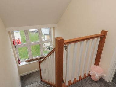 A stairwell with wooden and white banister and a window with a windowsill holding a vase and a piece of wood at Greenlee House in Seahouses
