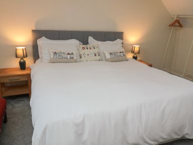A bedroom with a bed with decorative pillows and two bedside tables with lamps at Greenlee House in Seahouses