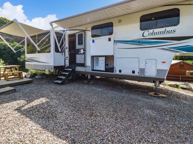 A recreational vehicle with awnings extended and steps leading to the door at Tickeydoo Tor Down Quarry in St Breward