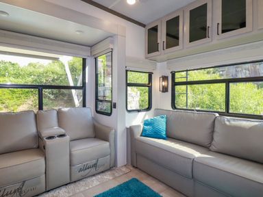 An interior room with two grey sofas a blue pillow a blue rug cabinets and multiple windows with a view of greenery at Tickeydoo Tor Down Quarry in St Breward
