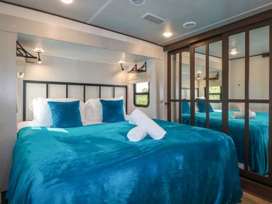 A bedroom with a blue bedspread white pillows and a mirrored wardrobe at Tickeydoo Tor Down Quarry in St Breward