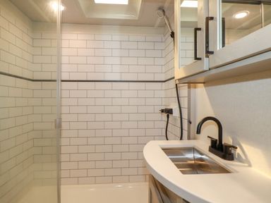 A bathroom with a shower area with white subway tiles and a sink with a black faucet at Tickeydoo Tor Down Quarry in St Breward