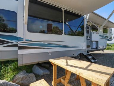 An outdoor picnic table next to a parked recreational vehicle with an awning extended at Tickeydoo Tor Down Quarry St Breward