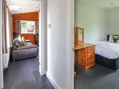 A hallway with a leather sofa visible through an open door and a bedroom with a wooden dresser and a bed at The Blacktail in Llanerch Park near St Asaph