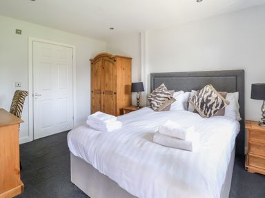 A bedroom with a bed and pillows a wooden wardrobe a desk and a chair at The Blacktail in Llanerch Park near St Asaph