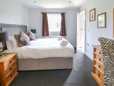 A bedroom with a double bed bedside tables a window with curtains and a wooden dresser at The Blacktail in Llanerch Park near St Asaph