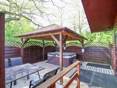 An outdoor patio with a gazebo covering a hot tub and a table with chairs at The Blacktail in Llanerch Park near St Asaph