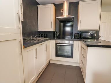 A kitchen with cabinets a sink an oven a microwave kettle and a toaster at The Buck in Llanerch Park near St Asaph
