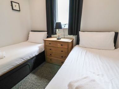 A bedroom with two single beds a wooden chest of drawers and a lamp on top at The Buck in Llanerch Park near St Asaph