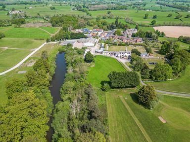An aerial view of a rural area with buildings a river trees fields and roads at The Buck in Llanerch Park near St Asaph