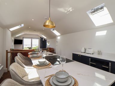 A kitchen and dining area with a countertop set with dishes and glasses at Victory View in Pendeen