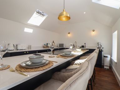 A kitchen with a marble countertop island set with plates bowls wine glasses and cutlery at Victory View in Pendeen
