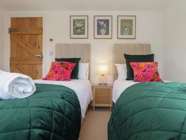 A bedroom with two single beds green bedding and pink floral pillows at Victory View in Pendeen